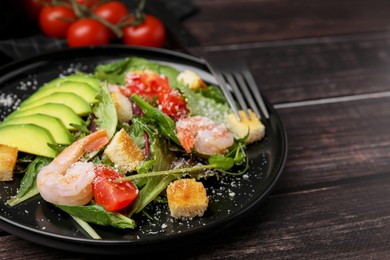 Photo of Delicious salad with croutons, avocado and shrimp served on wooden table, closeup. Space for text