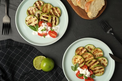 Photo of Flat lay composition with delicious grilled zucchini slices on black table