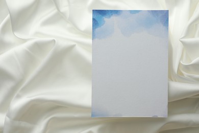 Photo of Blank invitation card on white fabric, top view. Space for text