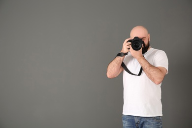 Male photographer with camera on gray background