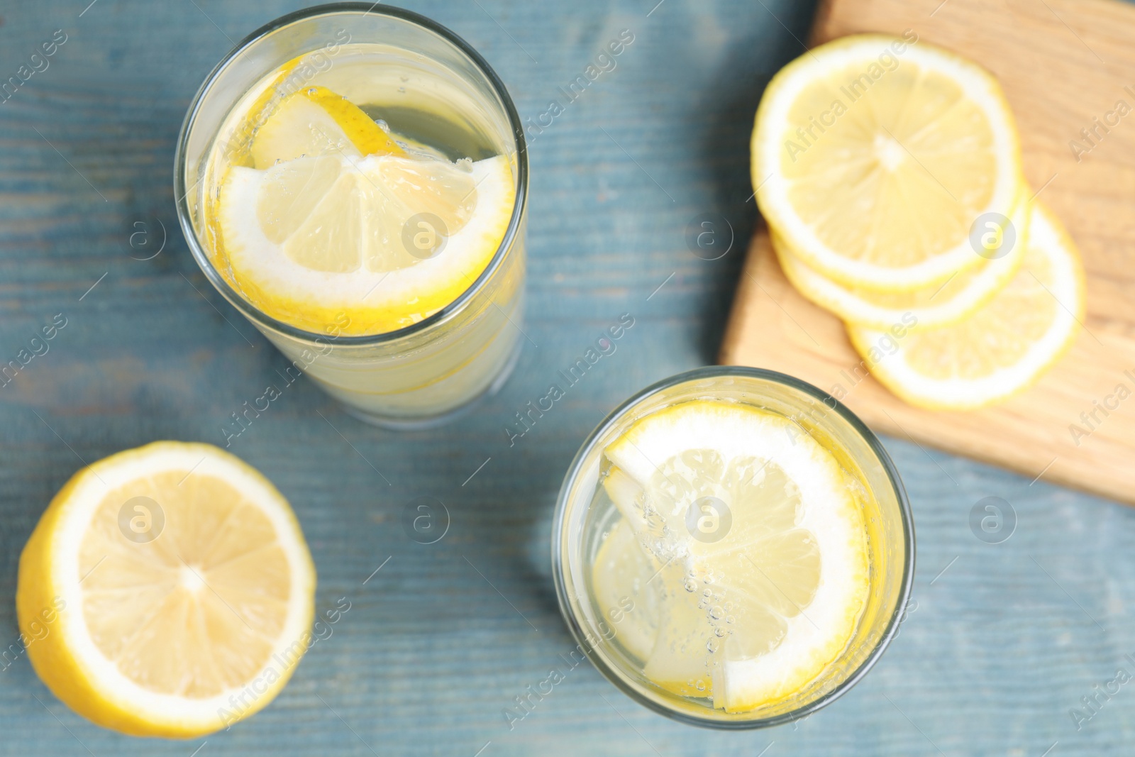 Photo of Soda water with lemon slices on blue wooden table, flat lay