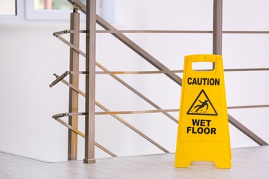 Photo of Safety sign with phrase Caution wet floor, indoors. Cleaning service