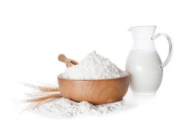 Photo of Wheat flour and jug of milk on white background