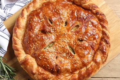 Photo of Tasty homemade pie and fresh rosemary on wooden table, flat lay