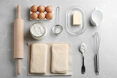 Photo of Flat lay composition with puff pastry dough and ingredients on grey table