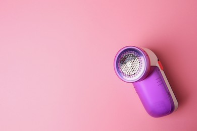 Modern fabric shaver on pink background, top view. Space for text