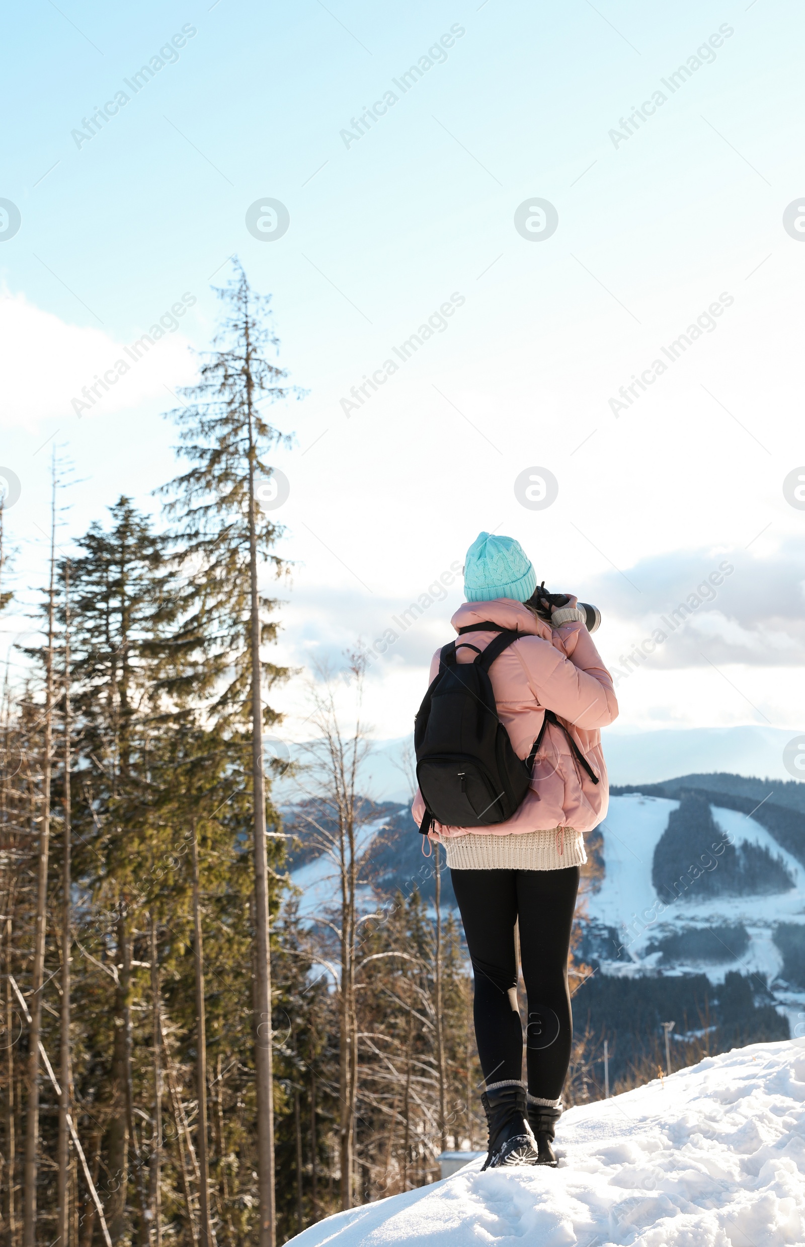 Photo of Young woman photographing beautiful mountain view during winter vacation