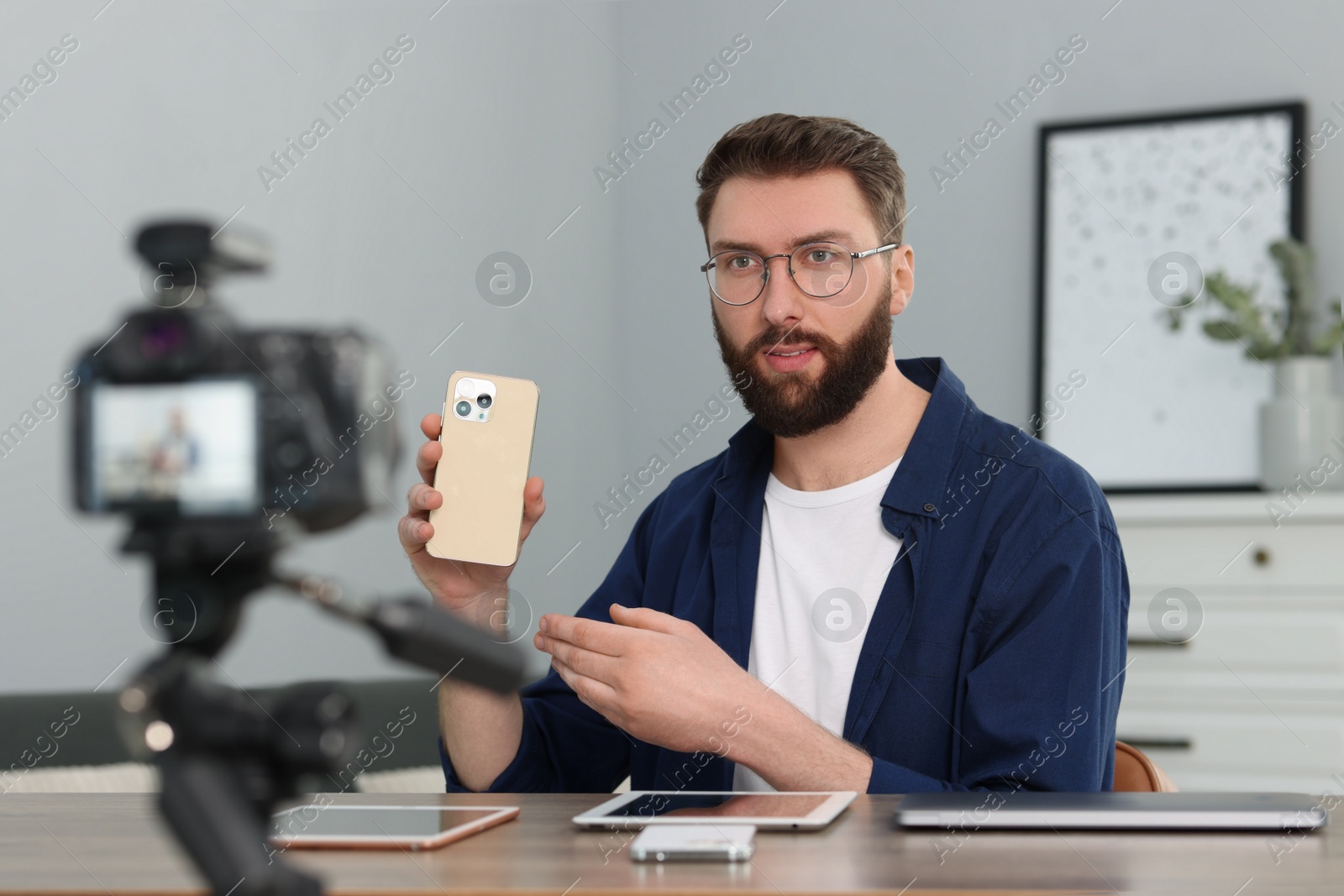Photo of Technology blogger with smartphone recording video review at home