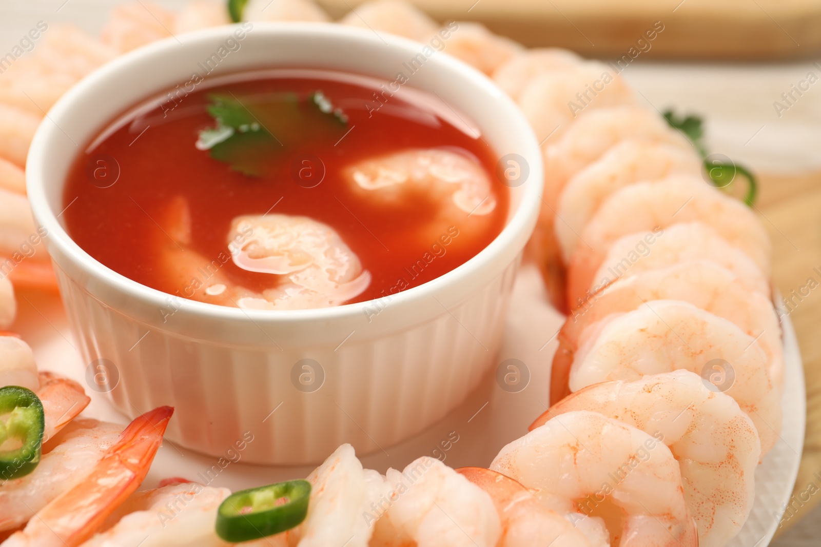 Photo of Tasty boiled shrimps with cocktail sauce, chili and parsley on table, closeup