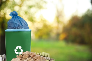 Waste bin with plastic bag full of garbage surrounded by garbage outdoors, space for text