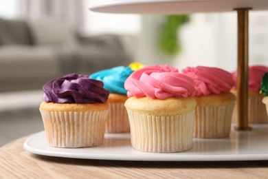 Delicious cupcakes with bright cream on wooden table indoors, closeup