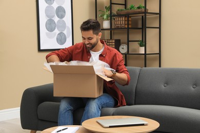 Photo of Man unpacking parcel at home. Online shopping