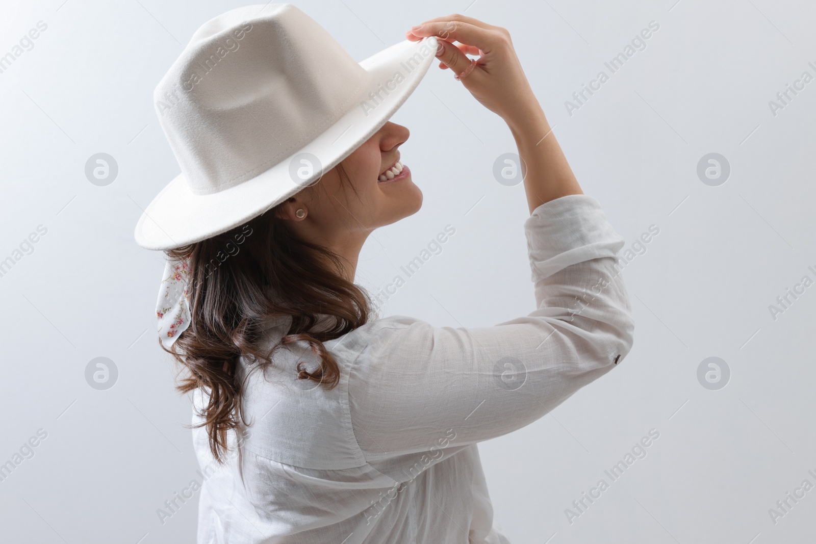 Photo of Happy young woman with hat and stylish bandana on light background