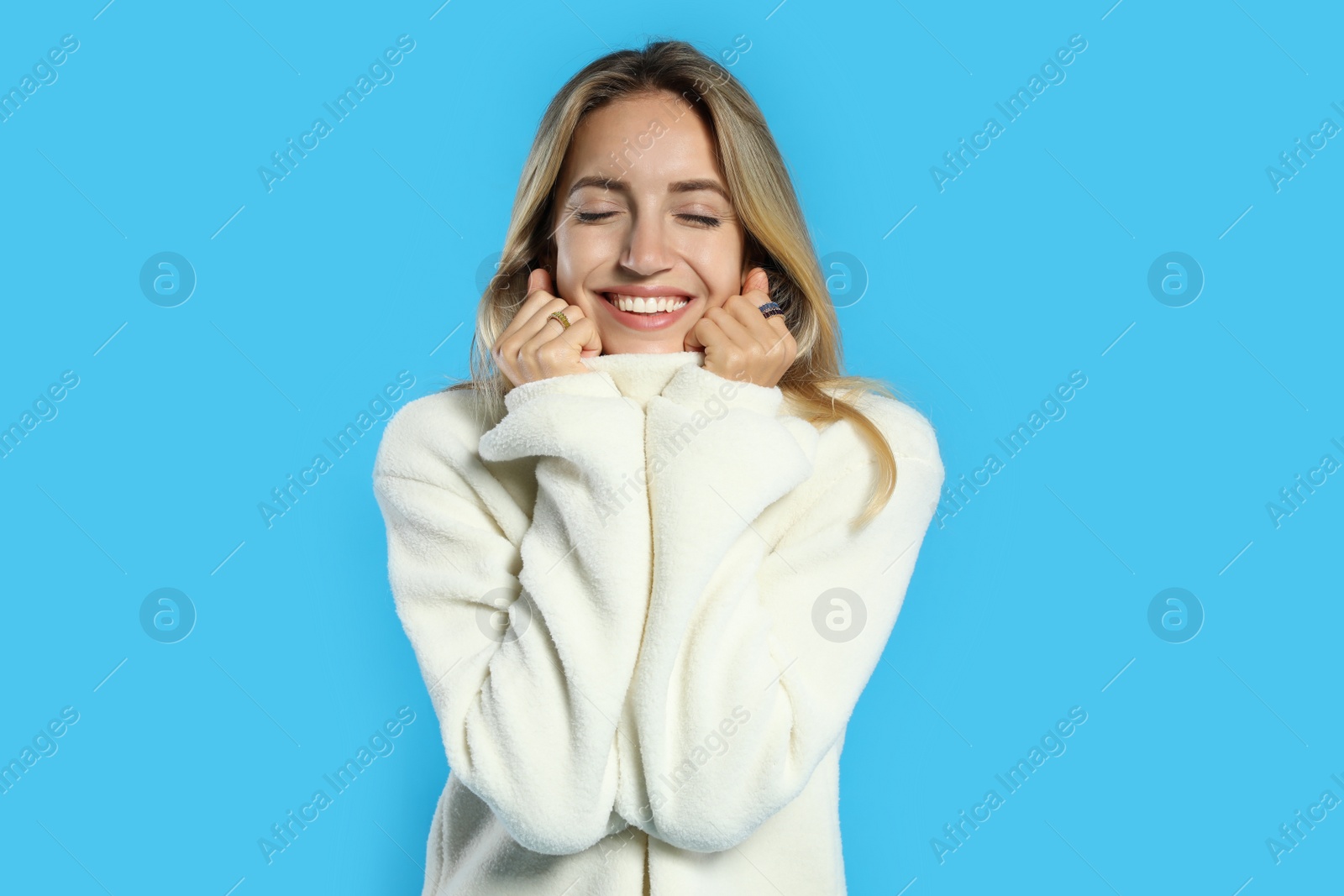 Photo of Beautiful young woman wearing knitted sweater on light blue background