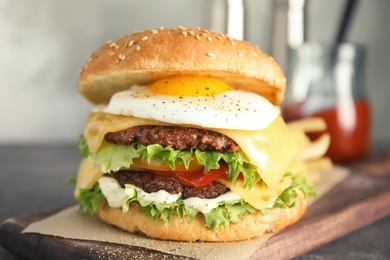 Photo of Tasty burger with fried egg on wooden board