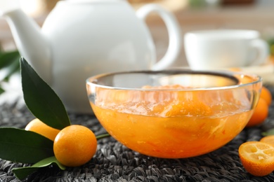 Delicious kumquat jam and fresh fruits on wicker mat, closeup