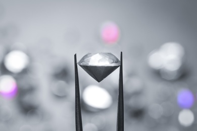 Photo of Tweezers with beautiful gemstone on blurred background