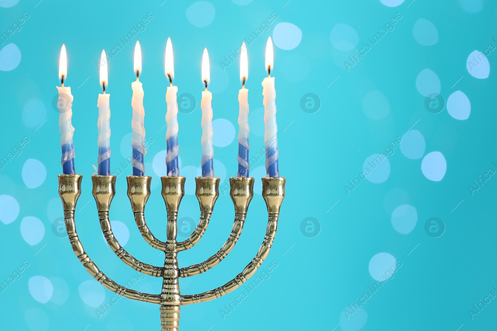 Photo of Hanukkah celebration. Menorah with burning candles on light blue background with blurred lights, space for text