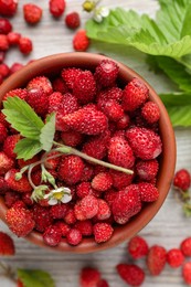 Fresh wild strawberries, flower and leaves on white wooden table, flat lay