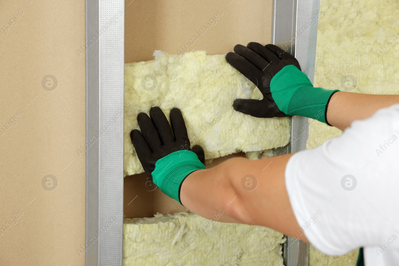 Photo of Worker installing thermal insulation material on wall, closeup