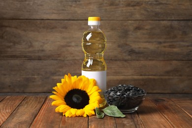 Photo of Sunflower cooking oil, seeds and yellow flower on wooden table