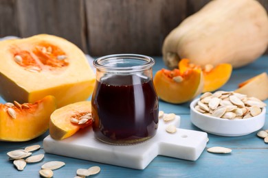 Photo of Fresh pumpkin seed oil in glass jar on blue wooden table