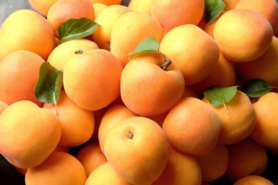 Photo of Delicious ripe sweet apricots with leaves as background, closeup view
