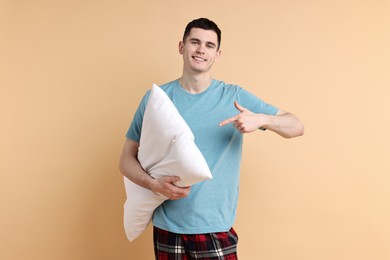 Photo of Happy man in pyjama holding pillow on beige background