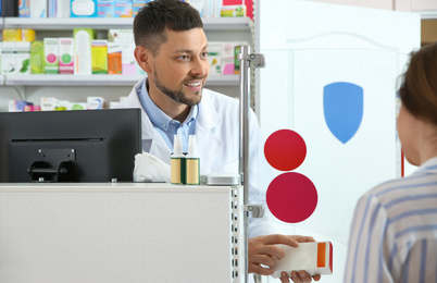 Professional pharmacist giving medicine to customer in drugstore