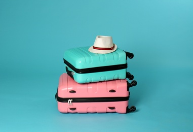 Photo of Stylish suitcases with hat on color background