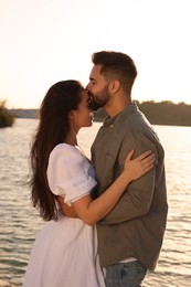 Beautiful couple kissing near river on sunny day