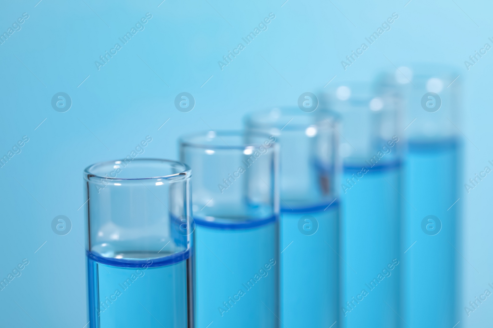 Photo of Test tubes with reagents on light blue background, closeup. Laboratory analysis