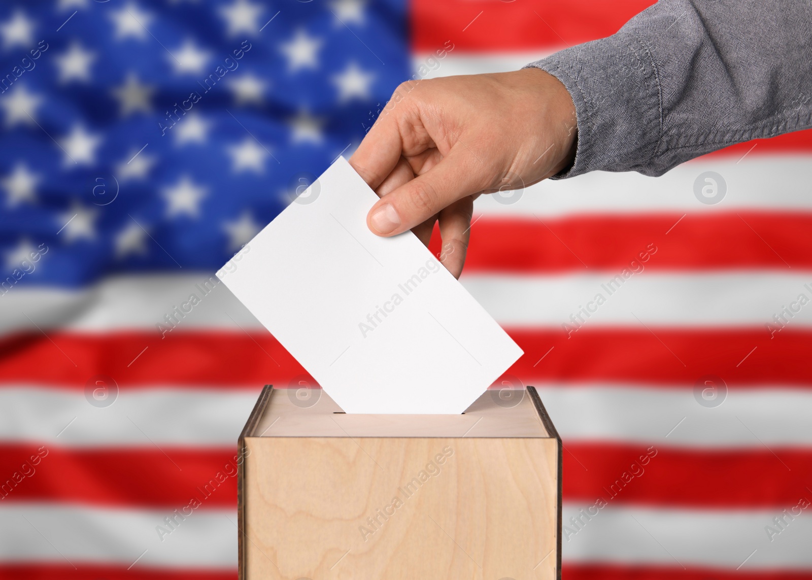 Image of Election in USA. Man putting his vote into ballot box against national flag of United States, closeup