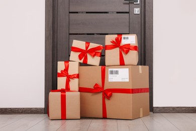 Photo of Christmas gift boxes on floor near door. Sending present by mail