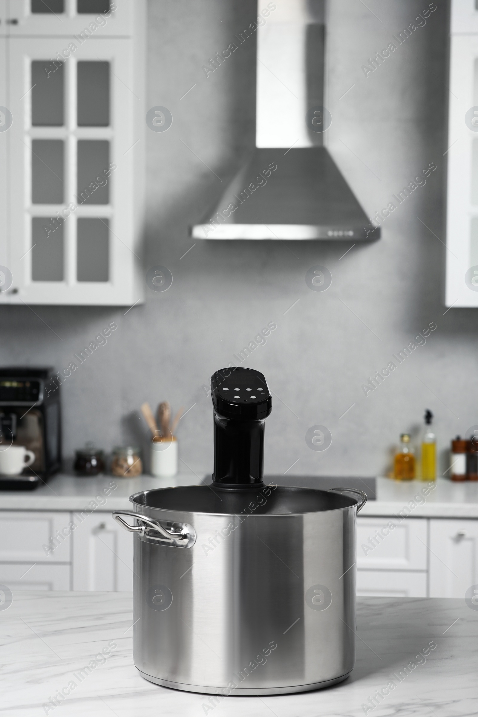 Photo of Pot with sous vide cooker on table in kitchen. Thermal immersion circulator