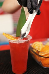 Photo of Male bartender preparing refreshing drink at table, closeup