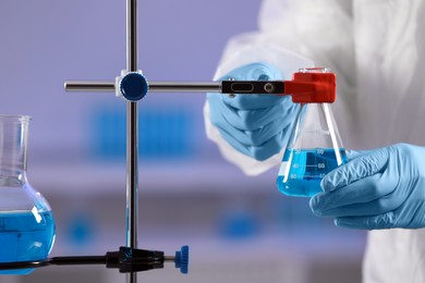 Photo of Scientist fixing flask on stand in laboratory, closeup