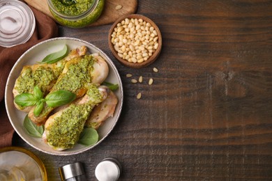 Delicious fried chicken drumsticks with pesto sauce and ingredients on wooden table, flat lay. Space for text