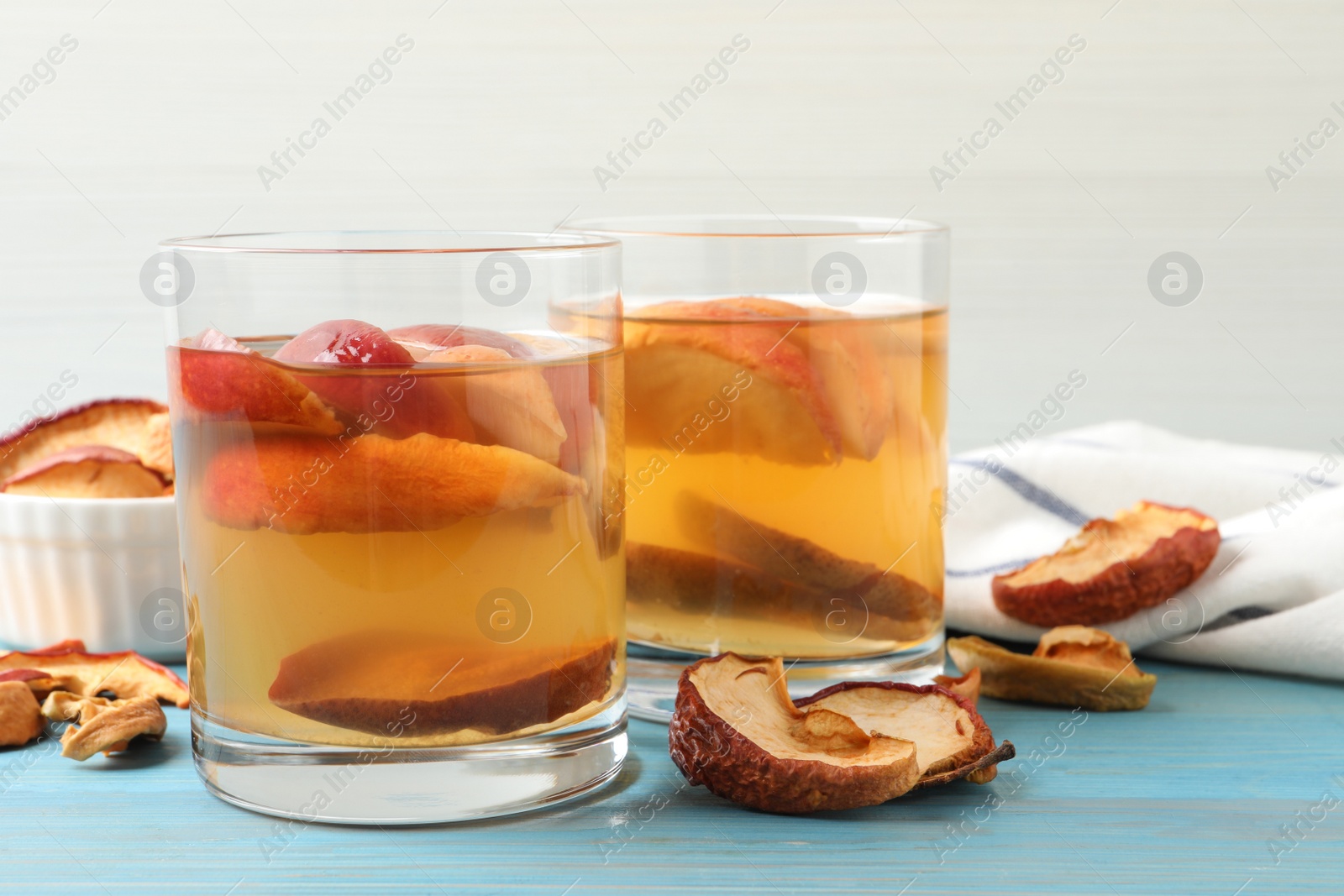 Photo of Delicious compot with dried apple slices on light blue wooden table