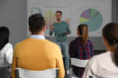 Male business trainer giving lecture in conference room with projection screen