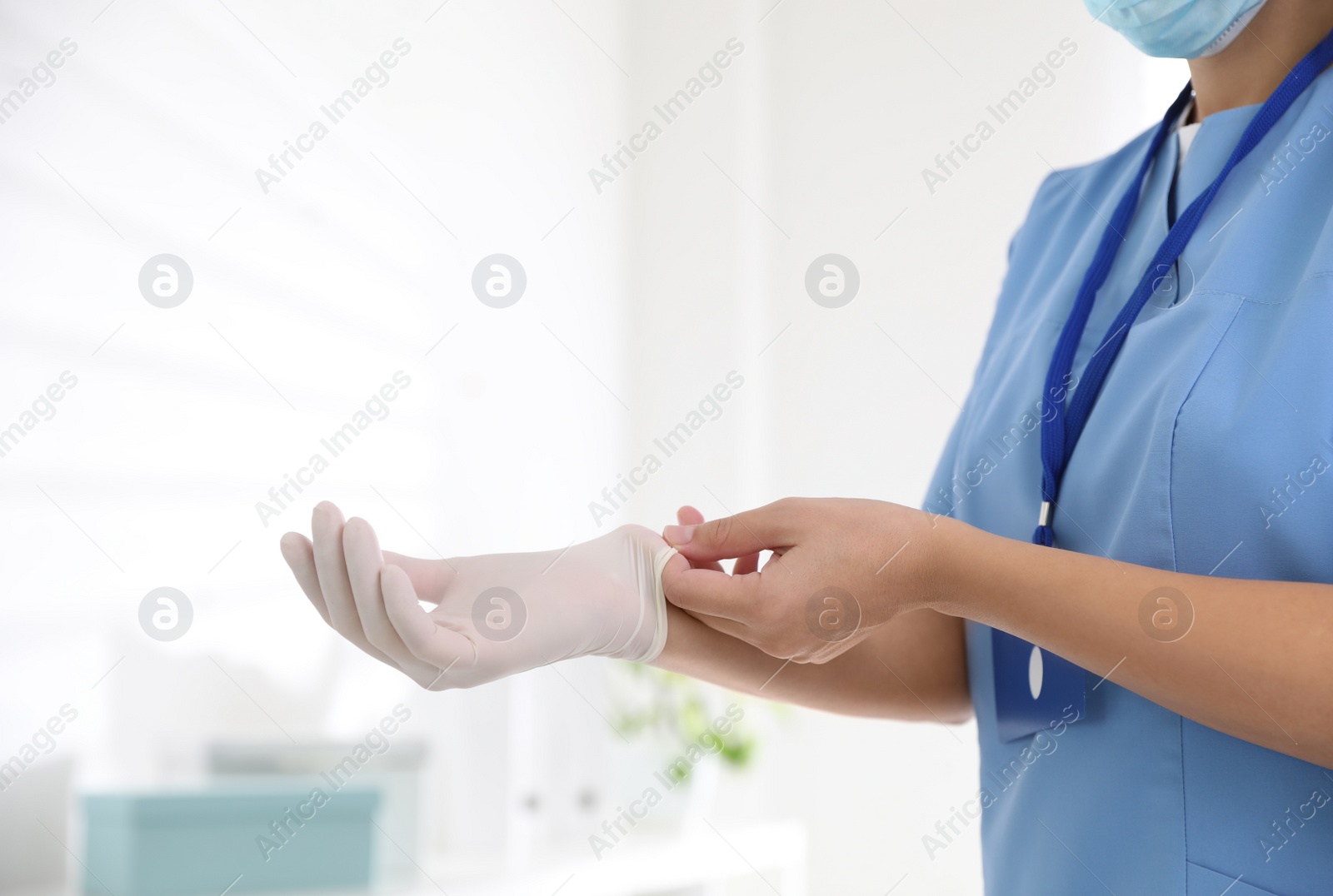 Photo of Doctor putting on medical gloves against blurred background, closeup