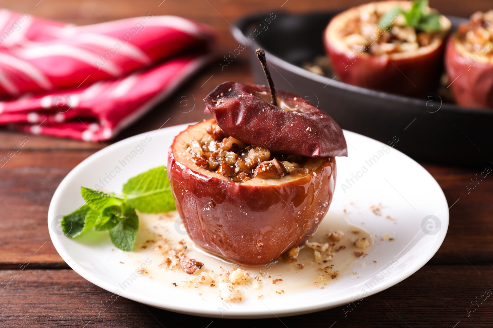 Photo of Tasty baked apple with nuts, honey and mint on wooden table, closeup