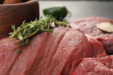 Photo of Piece of raw beef meat with microgreens against blurred background, closeup