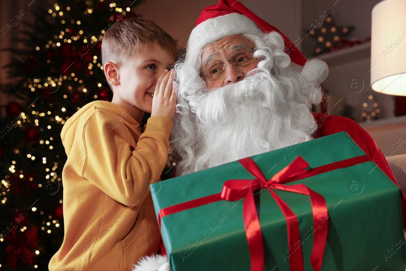 Photo of Merry Christmas. Little boy whispering his wish to Santa at home