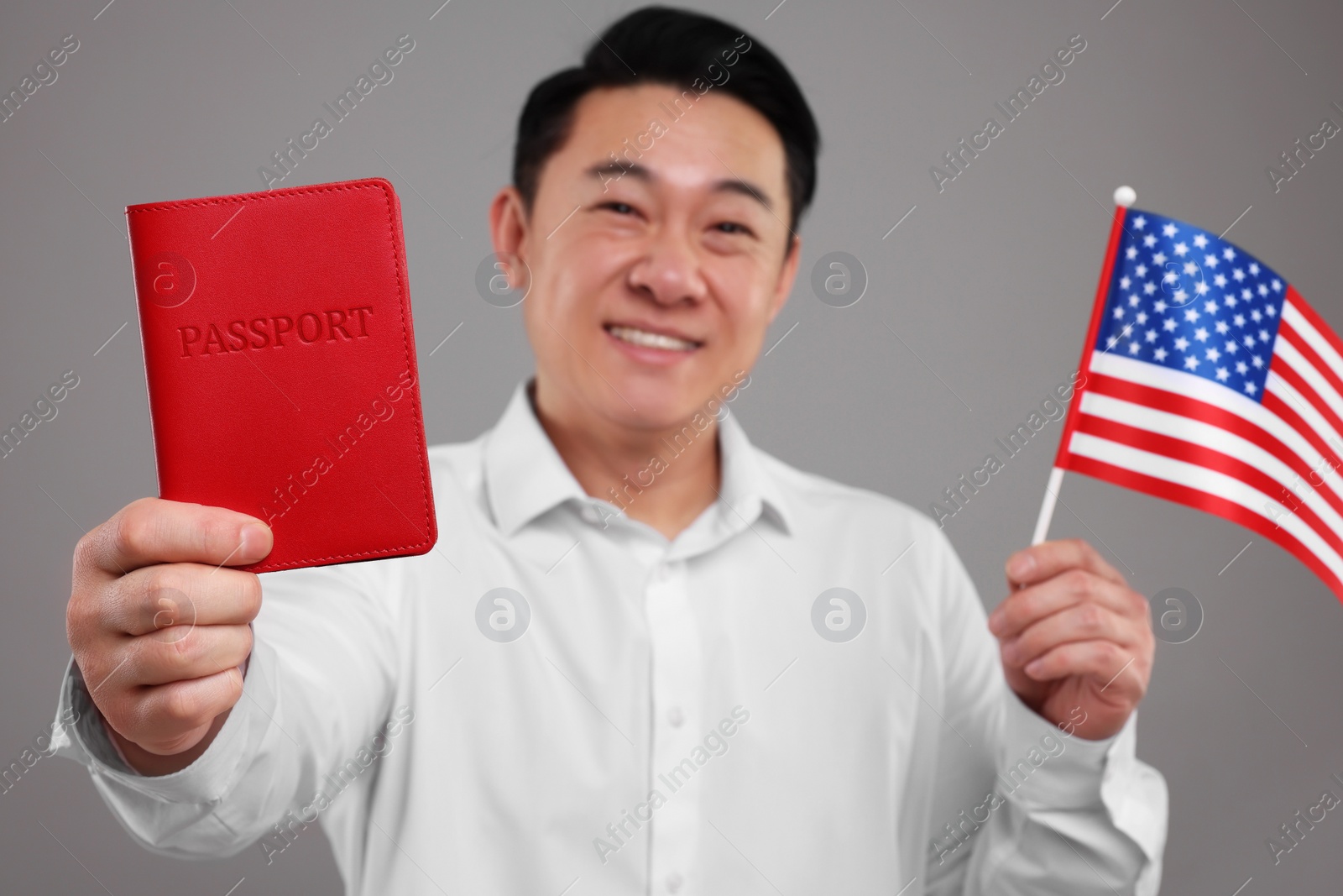 Photo of Immigration. Happy man with passport and American flag on grey background, selective focus