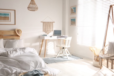 Stylish room interior with workplace, hanging chair and bed