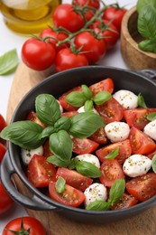 Photo of Tasty salad Caprese with mozarella balls, tomatoes and basil on table, above view