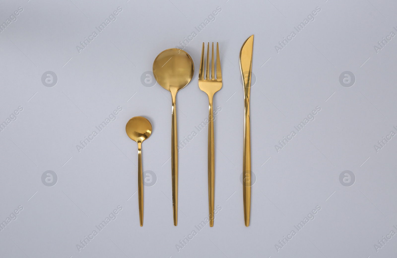 Photo of Stylish golden cutlery set on gray background, flat lay