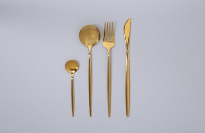 Stylish golden cutlery set on gray background, flat lay