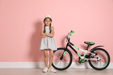 Photo of Portrait of cute little girl with bicycle near color wall
